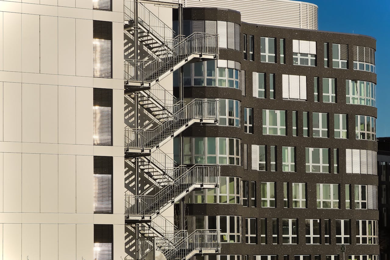 creative A contemporary building facade with steel staircases and glass windows under clear skies.