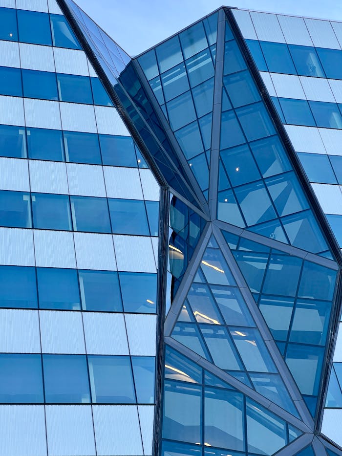 digital Close-up of a modern geometric glass facade with reflective blue windows.