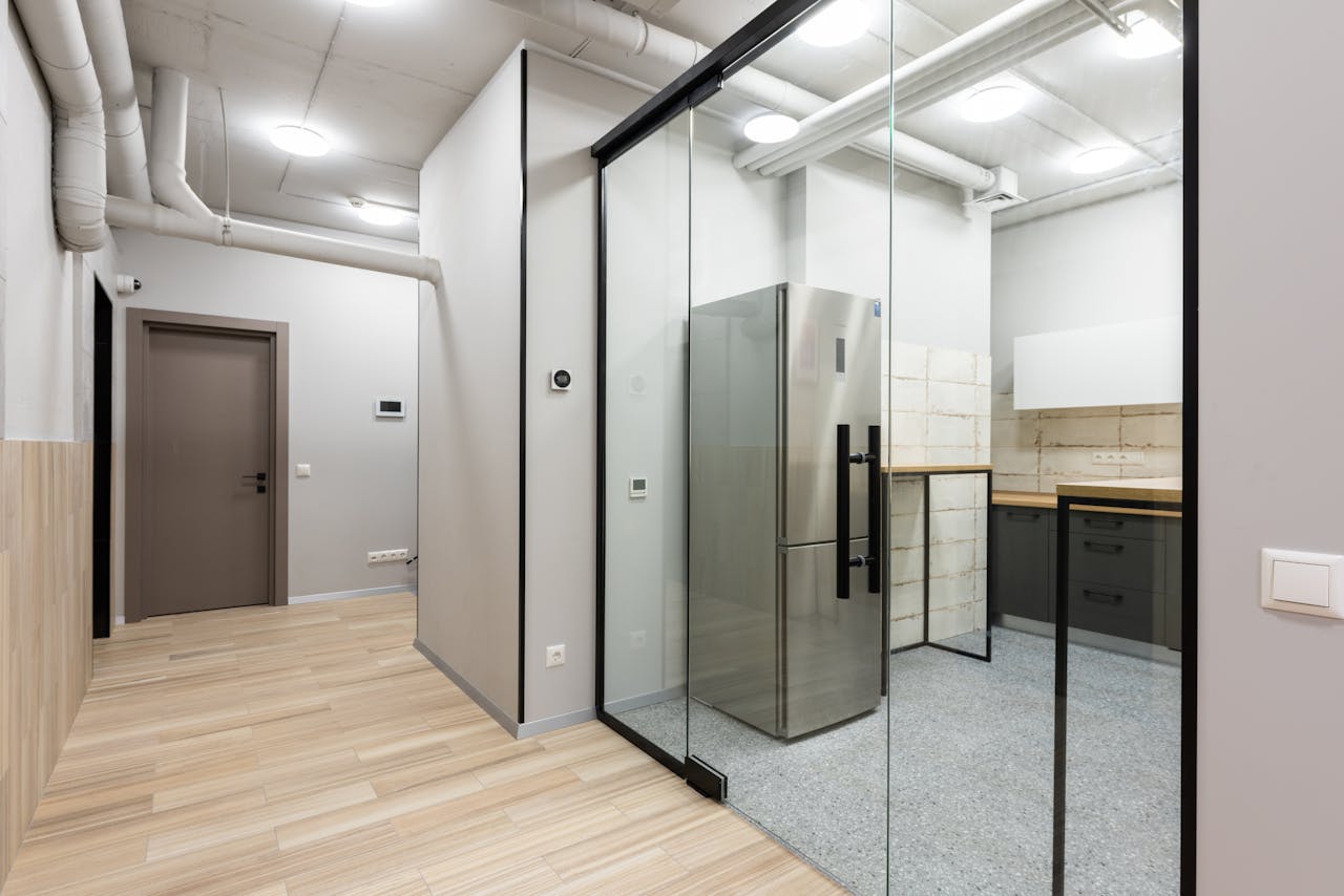 our-story Sleek and contemporary interior showcasing a kitchen area with glass partition and modern appliances.